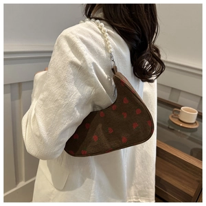 Detail of corduroy shoulder bag with strawberry print and elegant pearl strap
