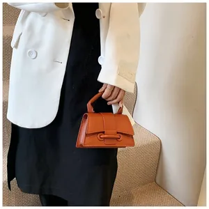 Close-up of orange litchi grain leather handbag with stylish metal ring buckle closure
