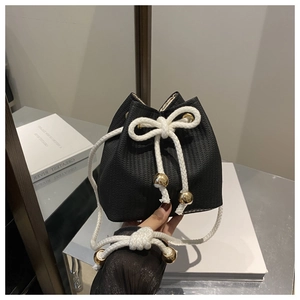 Close-up of black woven bucket bag with white rope handles and gold metallic details