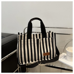 Détail du sac cabas rayé avec poignées noires et étiquette mode en cuir