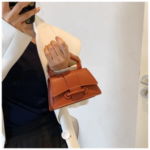 Detail view of mini lychee texture handbag in orange-brown leather worn as a shoulder bag