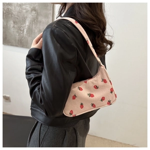 Détail d'un sac sous les bras en velours côtelé rose avec imprimé fraises sur un modèle