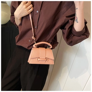 Close-up of pink-orange lychee leather mini bag with ring buckle and sleek shoulder strap
