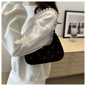 Detail of black corduroy shoulder bag with strawberry embroidery and pearl strap