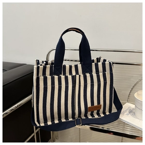 Détail des poches latérales sur un sac cabas en toile rayée avec écusson en cuir