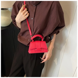 Close-up of red mini tote bag with litchi texture shown on a model for scale