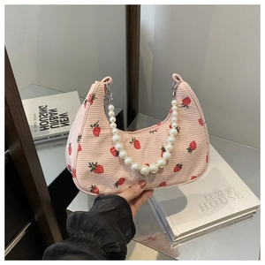 Detailed shot of pink corduroy shoulder bag with strawberry print and pearl handle