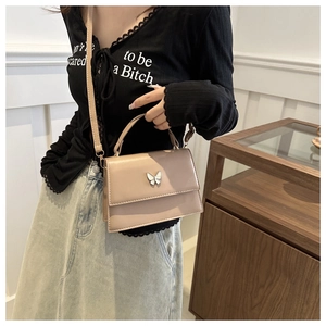Detail view of apricot crossbody bag with elegant butterfly buckle and adjustable strap