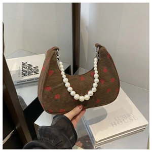 Detail of brown corduroy hobo bag with strawberry prints and pearl handle strap