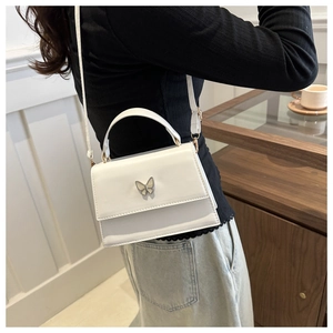 Detail of white glossy crossbody bag featuring elegant metal butterfly buckle and strap