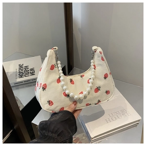 Detail of strawberry print corduroy bag featuring a decorative white pearl bead handle