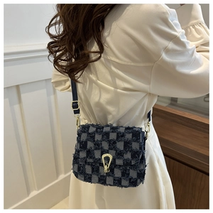 Modèle portant un sac bandoulière en denim à carreaux bleus avec boucle dorée et franges
