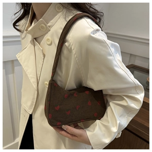 Détail du sac sous le bras en velours côtelé marron foncé avec motifs fraises rouges