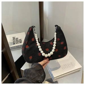 Detail of black corduroy hobo bag with strawberry print and white pearl chain handle