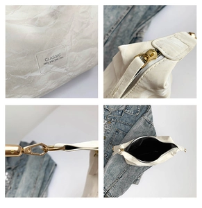 Detail of white tote bag showing marbled texture, gold zipper, and transparent brand patch