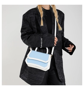 Detail of blue and white contrast flap bag showing the rigid structure and top handle