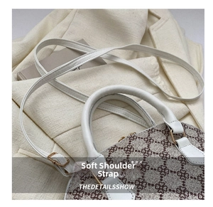 Detail showing the adjustable leather shoulder strap and clover pattern on beige shell bag