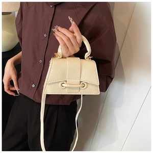 Detail of cream beige lychee pattern leather handbag with a flap and decorative strap