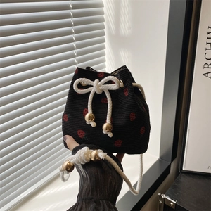 Minimalist black corduroy drawstring bucket bag with red strawberry print and gold metal balls