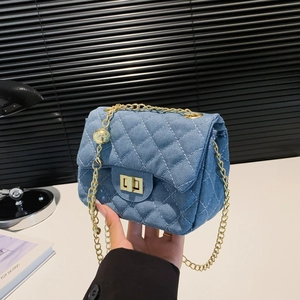 Blaue Denim Umhängetasche mit Steppmuster und Goldkette, in der Hand gehalten