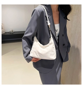 Detail of white soft leather hobo bag with pearl strap and golden hardware accents