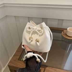 Elegant white woven bucket bag with gold spherical accents and thick rope drawstring