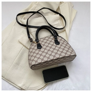 Chic shell crossbody bag with clover pattern next to a phone for size reference