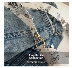 Détail macro des anneaux dorés et de la bandoulière à motif papillon sur sac denim