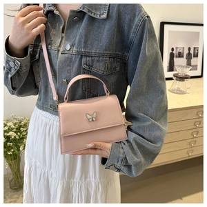 Detailed view of pink square handbag with butterfly metallic clasp and matte leather texture