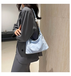 Macro detail of light blue wrinkled tote bag featuring decorative oversized pearl strap accent