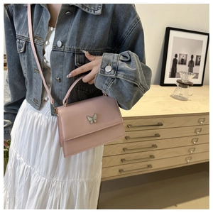 Detail of pink fashion handbag with white butterfly buckle and slim shoulder strap