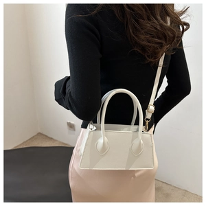 Rear view of a model wearing a white mini trapezoid handbag with gold hardware detail