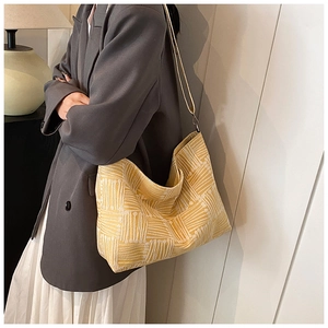 Detail of yellow and white striped knit tote bag showing fabric texture and slouchy shape