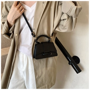 Detail shot of black textured leather handbag with a top handle and adjustable strap
