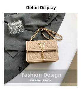 Detailed view of beige quilted chain bag with gold V-logo and tassel on grey blazer
