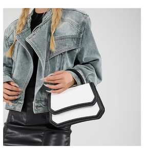 Close-up of contrast stitching on a black and white minimalist flap handbag