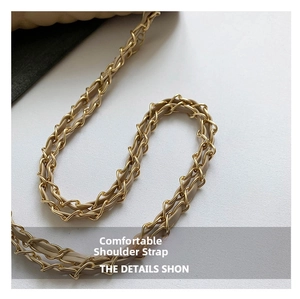 Detail of a golden metal chain strap interwoven with beige leather for crossbody bags