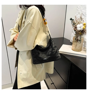 Detail of black wrinkled fabric bag with amber bead accents and a classic label