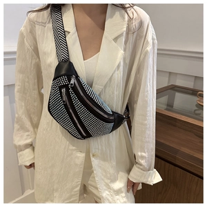 Detail of black rhinestone chest bag featuring a textured woven strap and silver zippers