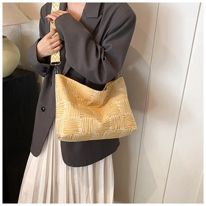 Close-up of mustard yellow knit shoulder bag with white geometric patterns and wide strap