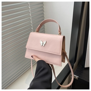 Detailed view of pink leather handbag featuring an elegant white butterfly metal buckle