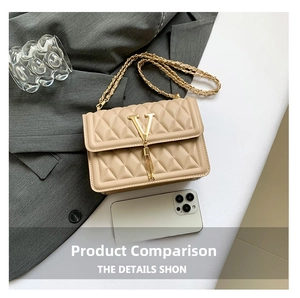 Detail of beige quilted crossbody bag with gold V logo and tassel against a grey suit background