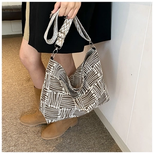 Detail of striped woven tote bag with adjustable wide strap and brown geometric pattern