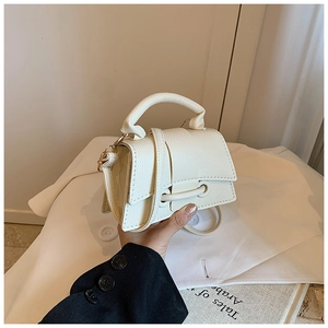 Detail of creamy white litchi pattern leather handbag with flap and slim shoulder strap