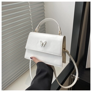 Detailed view of white PU leather crossbody bag featuring an elegant metal butterfly buckle