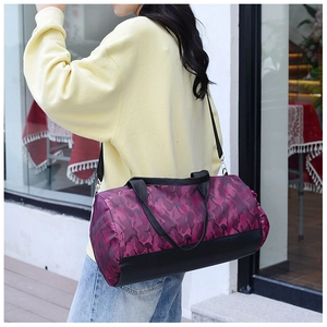 Detail view of purple camouflage duffel bag with black base and adjustable strap