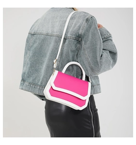 Detail showing contrast magenta flap and white leather base of the shoulder bag