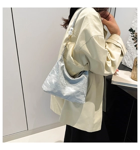 Detail of silver pleated shoulder bag with large pearl accents on straps and metallic texture