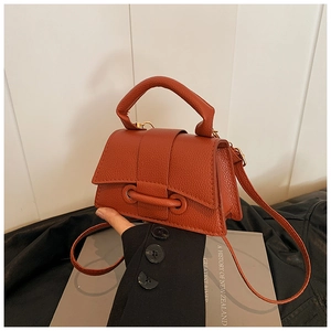 Close-up of orange-brown litchi pattern leather handbag with elegant top handle