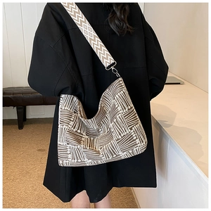 Detail of geometric pattern woven hobo bag with adjustable wide shoulder strap on model